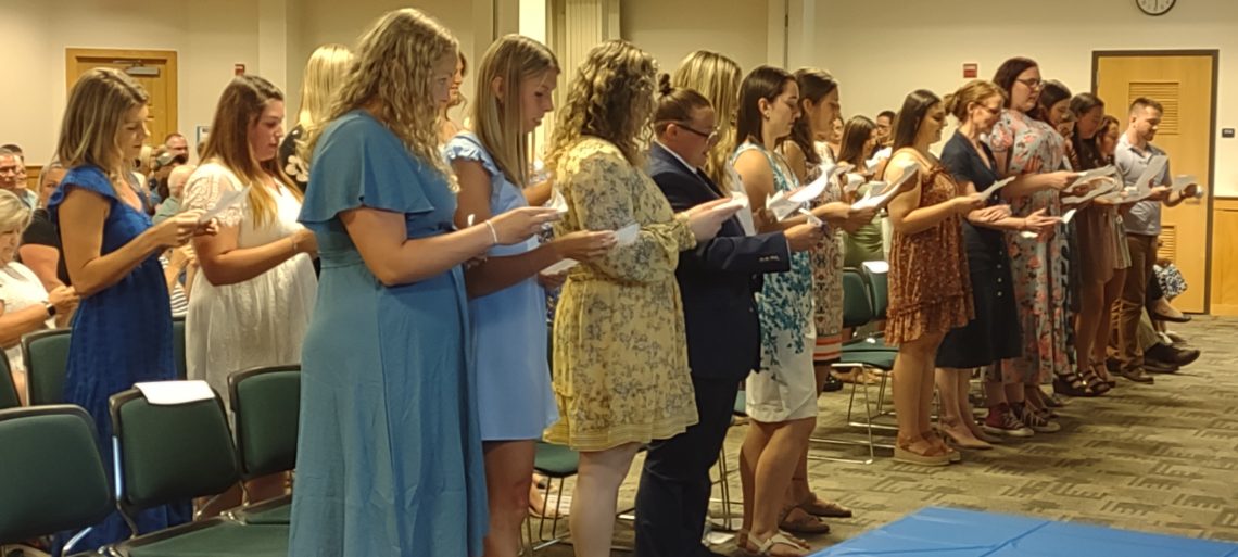 OT students standing and reading at pinning ceremony.