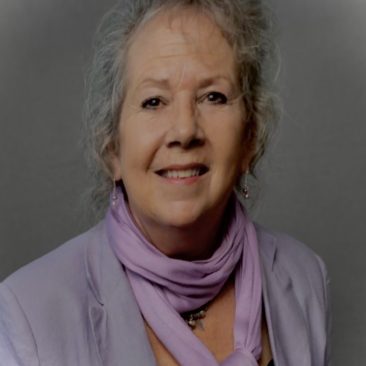 Photo of Brenda. She is wearing a purple scarf and purple jacket in her headshot.