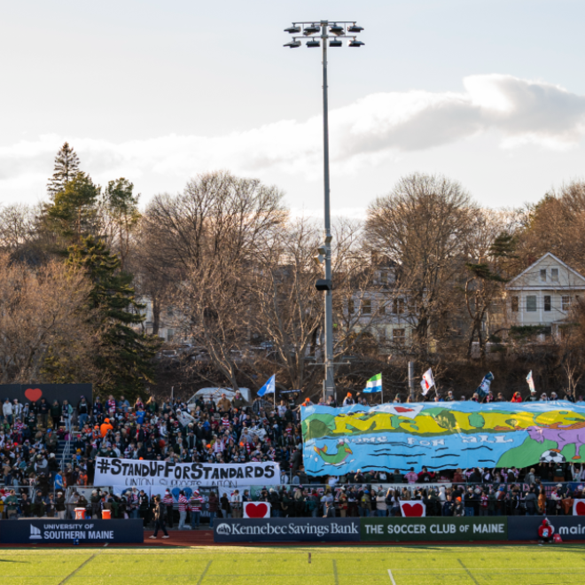 Fitzpatrick Stadium on a sunny day in Portland, Maine. The University of Southern Maine's logo can be read as a sponsor on the field-level boards.