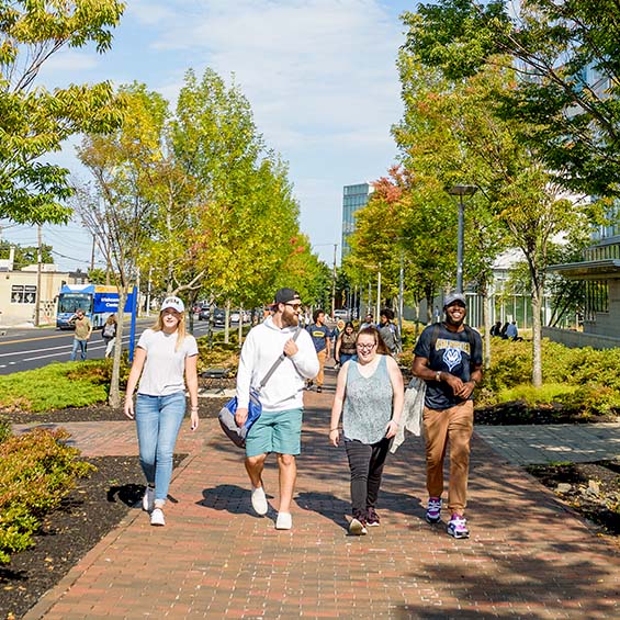 Four students walking up Bedford Street outside the Wishcamper Center on a sunny autumn day.