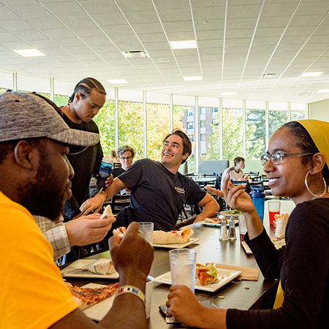A group of students sharing a meal and lively conversation in Brooks Dining Hall on our Gorham campus.
