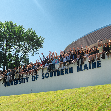 Cheering students sitting on the Gorham campus USM wall.