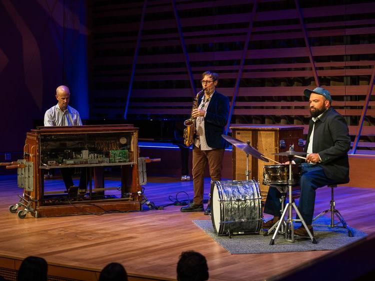 Mike McGinnis and pianist and drum kit player performing.