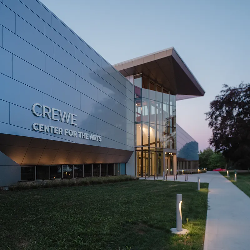 The Crewe Center at dusk. Several small lights line the path to the entrance.