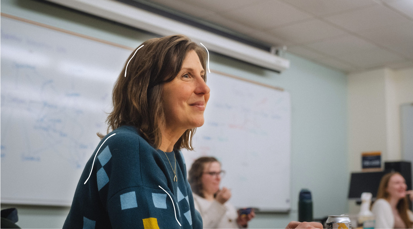 A professor smiles while engaging with students during a classroom discussion
