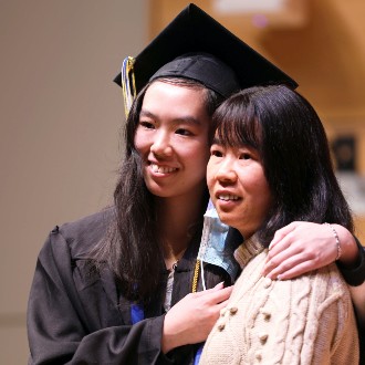 A graduate enjoys a hug after receiving her pin at the December 2022 Nursing Convocation ceremony.