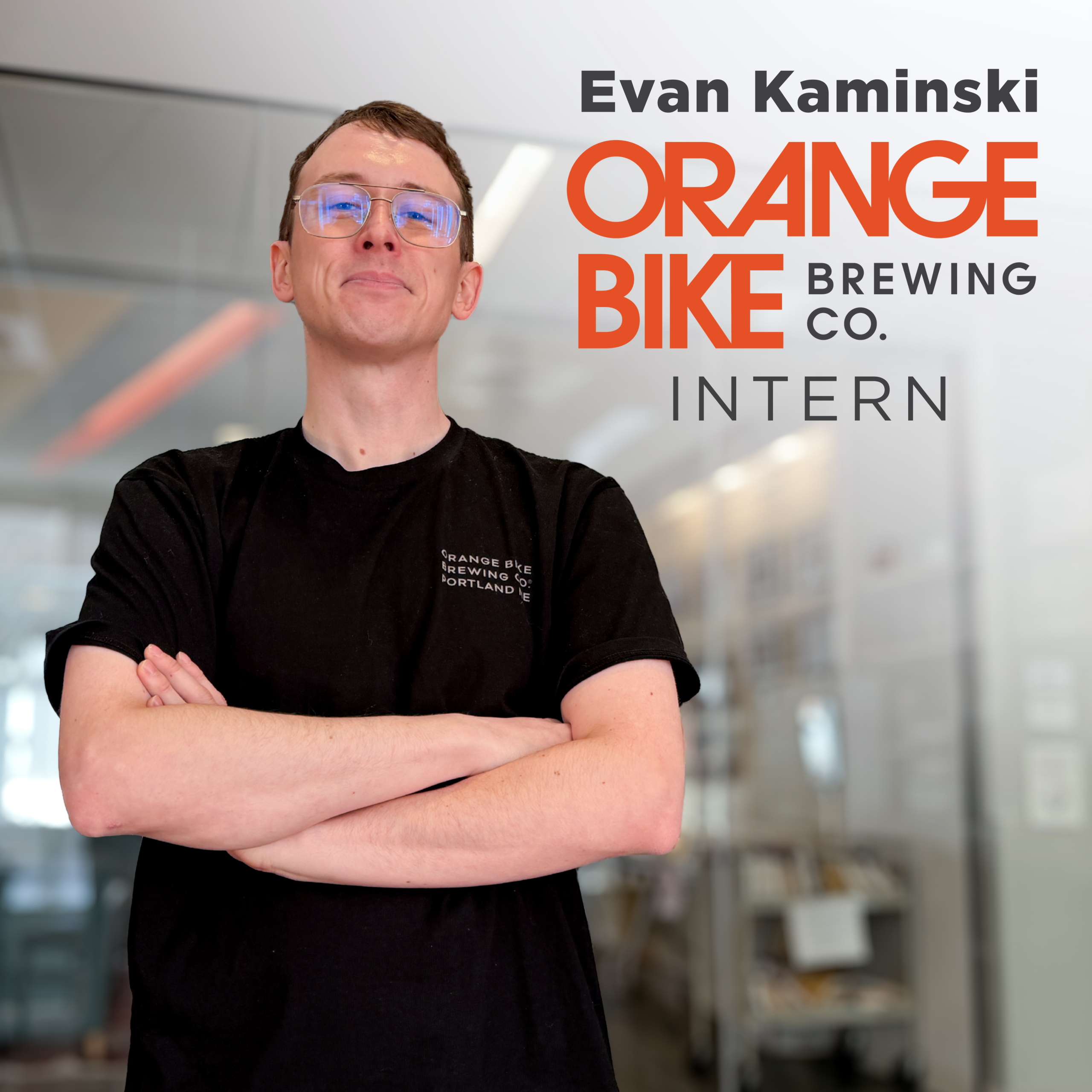 Evan Kaminski '26 stands for a photo op next to a rendered in Orange Bike Brewing Company Logo indicating his internship with them.