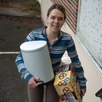 With arms full of furnishings and food, a student moves into Upton-Hastings Hall.