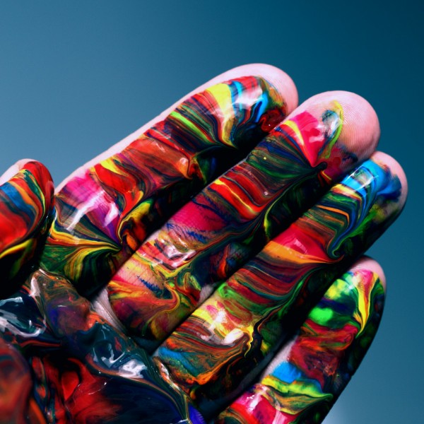 A hand with multi-color paint swirled across it.