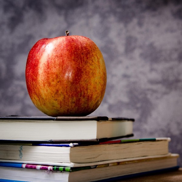 An apple sits on a stack of books.