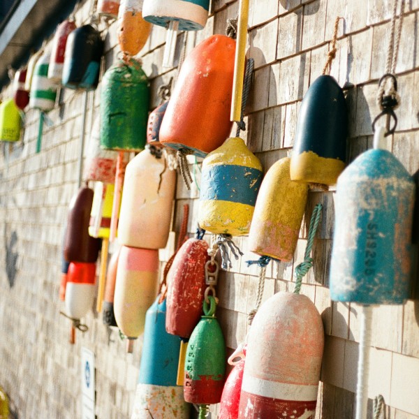 Multi-colored lobster buoys hang on the side of a shack