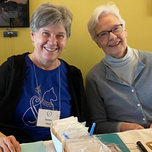 Two OLLI members sit behind a welcome table with name tags.