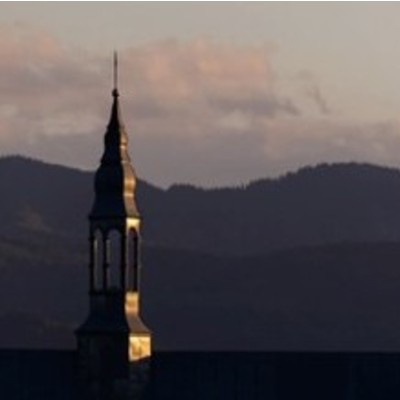The steeple of a church in front of a mountain range.