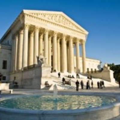 The Supreme Court building in Washington D.C. with its grand neoclassical architecture, marble columns, and a fountain in the foreground.