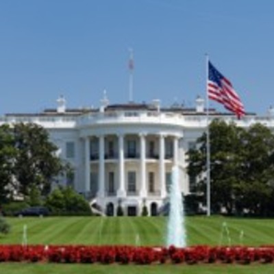 The White House with an American flag and a fountain on a sunny day.