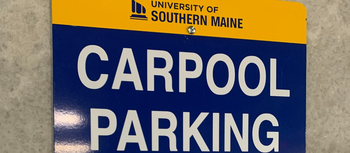 Picture of a sign that says Carpool Parking with the University logo above it.