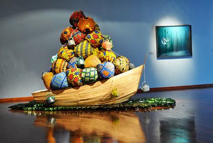 sculpture of boat holding balls with African Prints entitled Road to Exhile; by artist Barthélémy Toguo