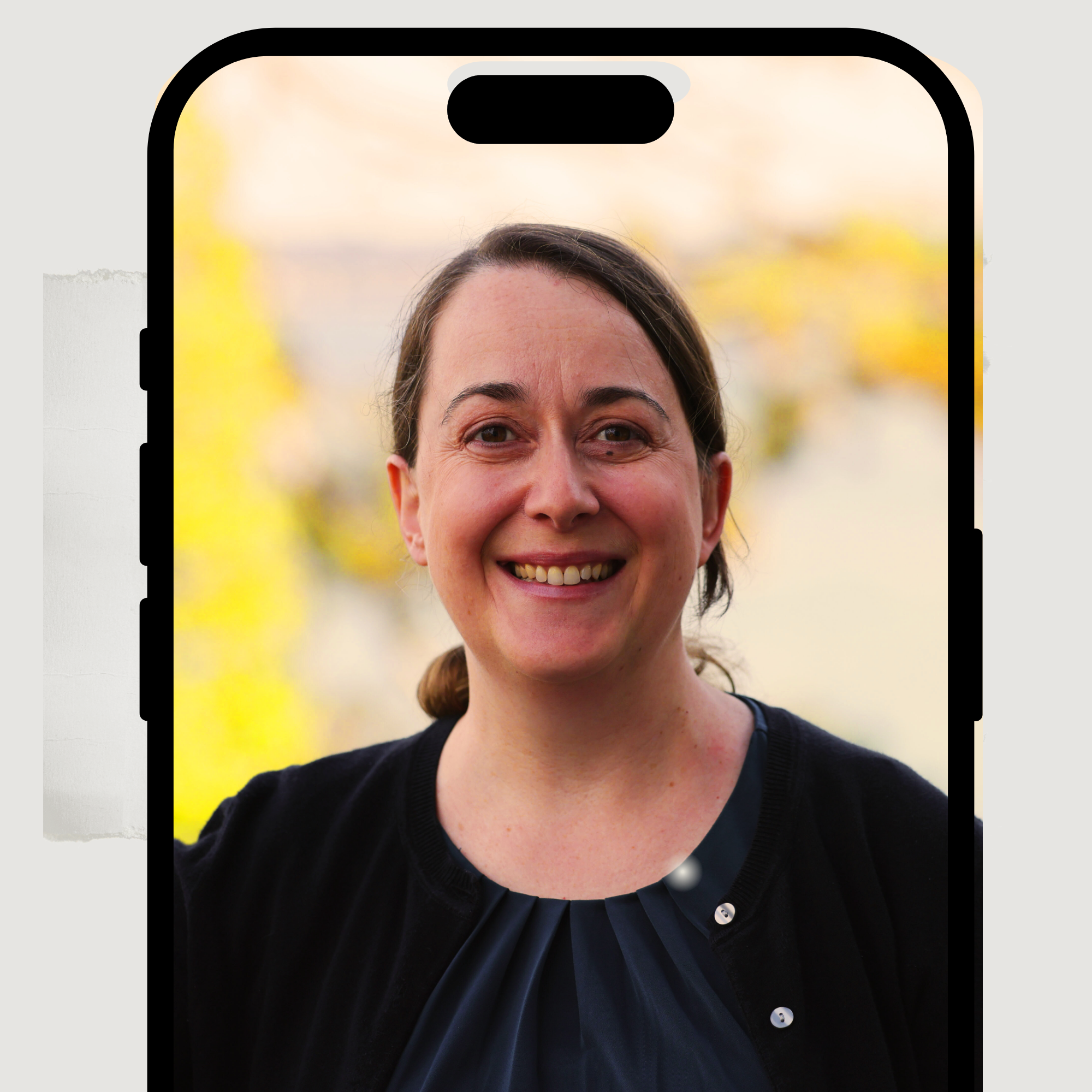 Professor Frost-Arnold headshot in nature with small body of water in the background as seen on a cell phone