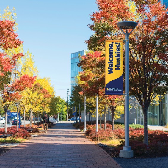 USM Portland campus with trees in fall foliage and Welcome, Huskies! sign