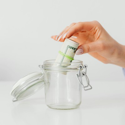 hand putting a rolled up bundle of dollar bills into a jar