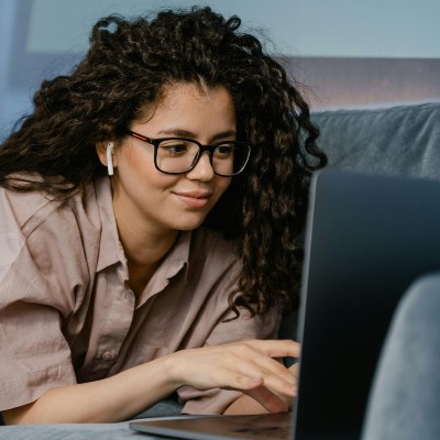 person of color looking at a laptop screen in a relaxed environment