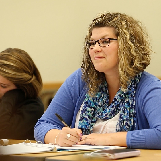 A student sits at a tabling and takes notes during class.