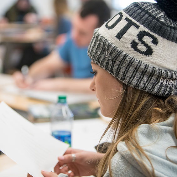 A student wearing a navy and white Patriots winter hat in a classroom on our Portland campus.