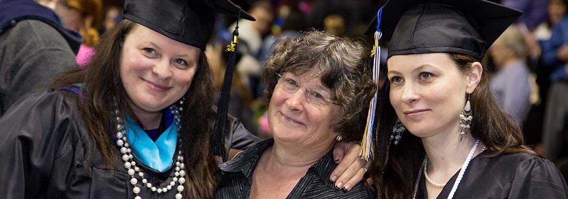 Two graduates pose with their mother at one of our Commencement ceremonies. The graduate on the left just earned a Master’s degree. The graduate on the right just earned a Bachelor’s degree.