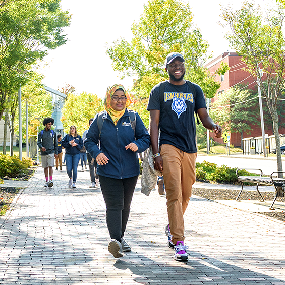 Students outside on a sunny autumn day, walking down Bedford Street on our Portland campus. Several are wearing clothing featuring the USM logo.