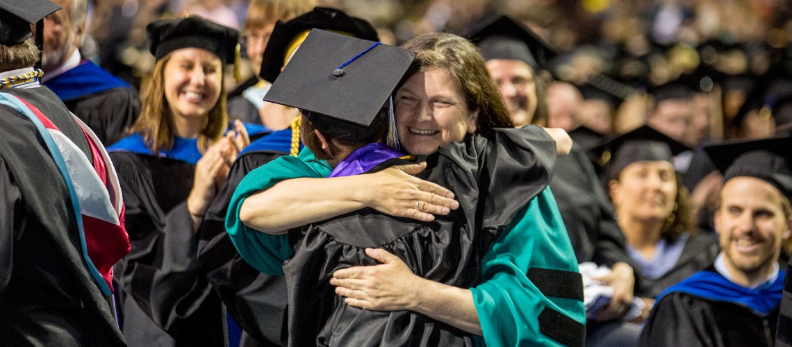 A professor hugging a student at commencement