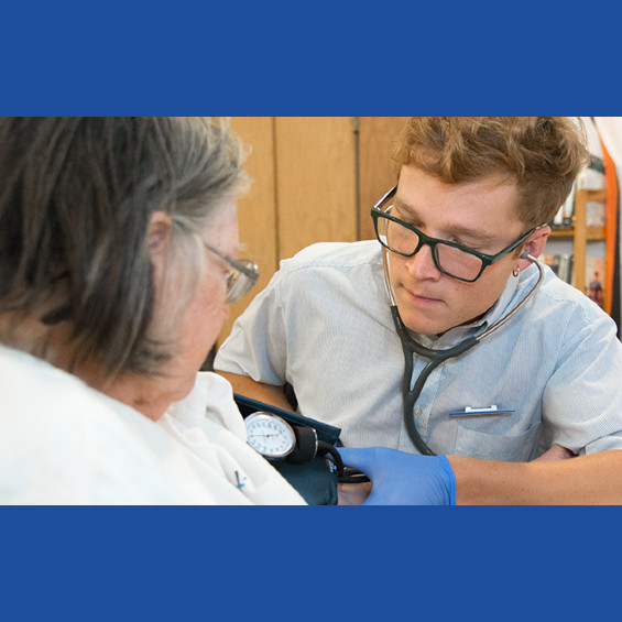 Nursing student take blood pressure measurement on community member.