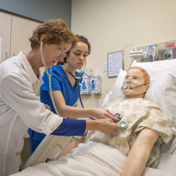 A student and faculty member work with a simulation mannequin.