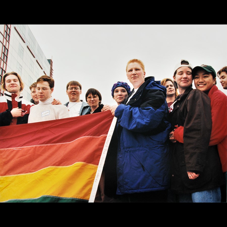 A group of people outdoors holding a rainbow flag