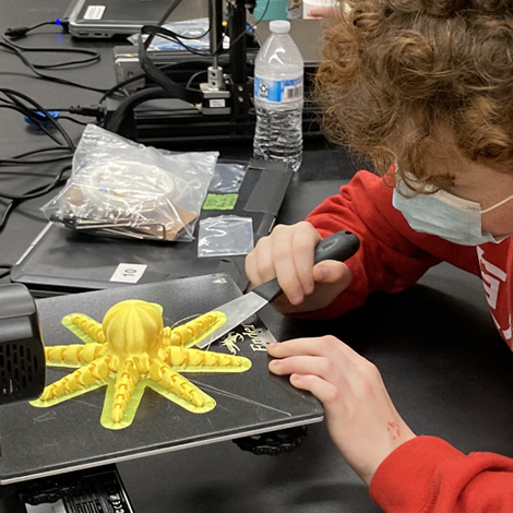 Camper removing finished 3D print of an octopus