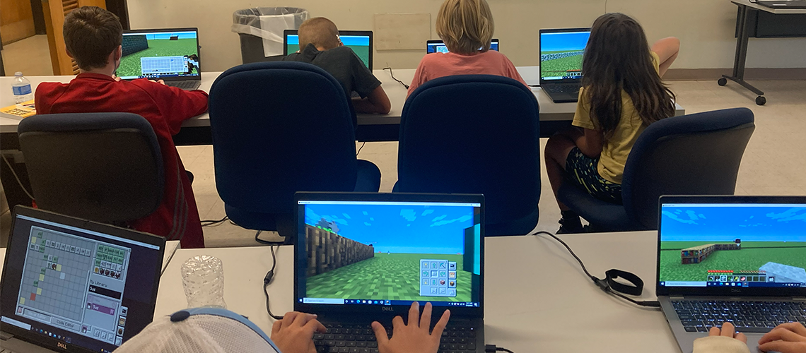 Students sitting at laptops, using Minecraft to code