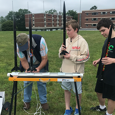 Instructor & students loading rockets onto a launching device