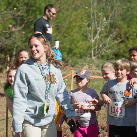 A female USM student working with a group of pre-teen children at an outdoor event.