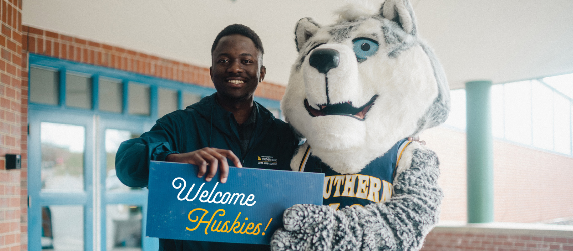 Champ the Husky standing with student and sign reading "Welcome Huskies!"