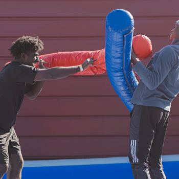 Two students battling with padded logs