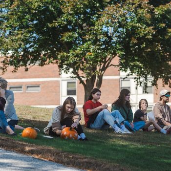 Attendees of Octoberfest sitting on a hill.