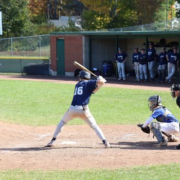 A Husky athlete swinging at a ball during a baseball game.