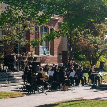 Music students playing at an outdoor band concert directed by Dr. Will Kinne.