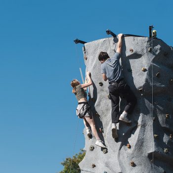 A pair of students climbing a rock wall at Octoberfest.