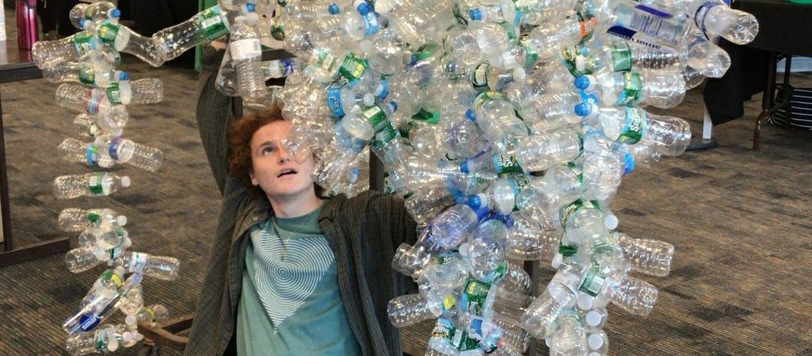 Student making art with hundreds of plastic bottles