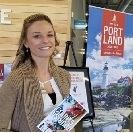 Lainey Minotti standing next to Portland Maine tourism sign