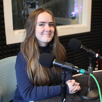 USM student Emma Brearley sits at a microphone at the WMPG studio on the USM Portland Campus