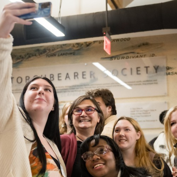 Alumni taking a selfi in front of the McGoldrick donor wall