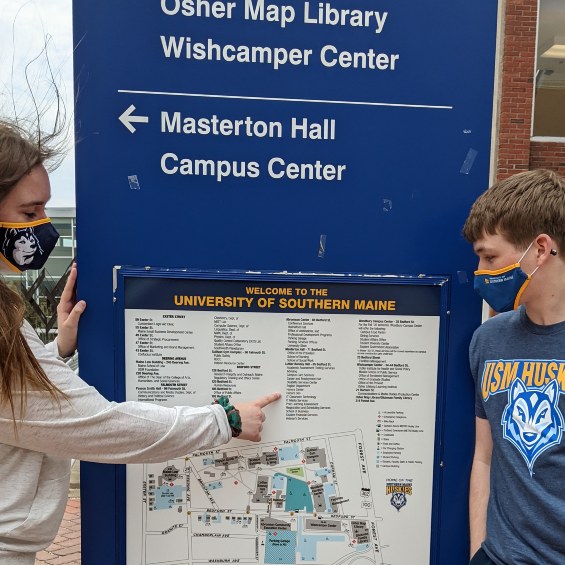 Two students pointing out the different location around the Portland USM Campus on the map outside