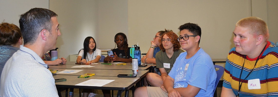 Students sit in a classroom listening to a guest speaker.