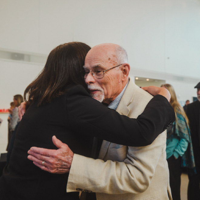 President Edmondson and Dr. Smith Embrace in gallery hall of Crewe Center